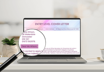 A laptop with a magnifying glass showing the contact information and salutation when addressing a cover letter