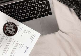 An placeholder hero image for an article on follow up emails after interviews, showing a CV placed artfully on top of a MacBook personal computer.